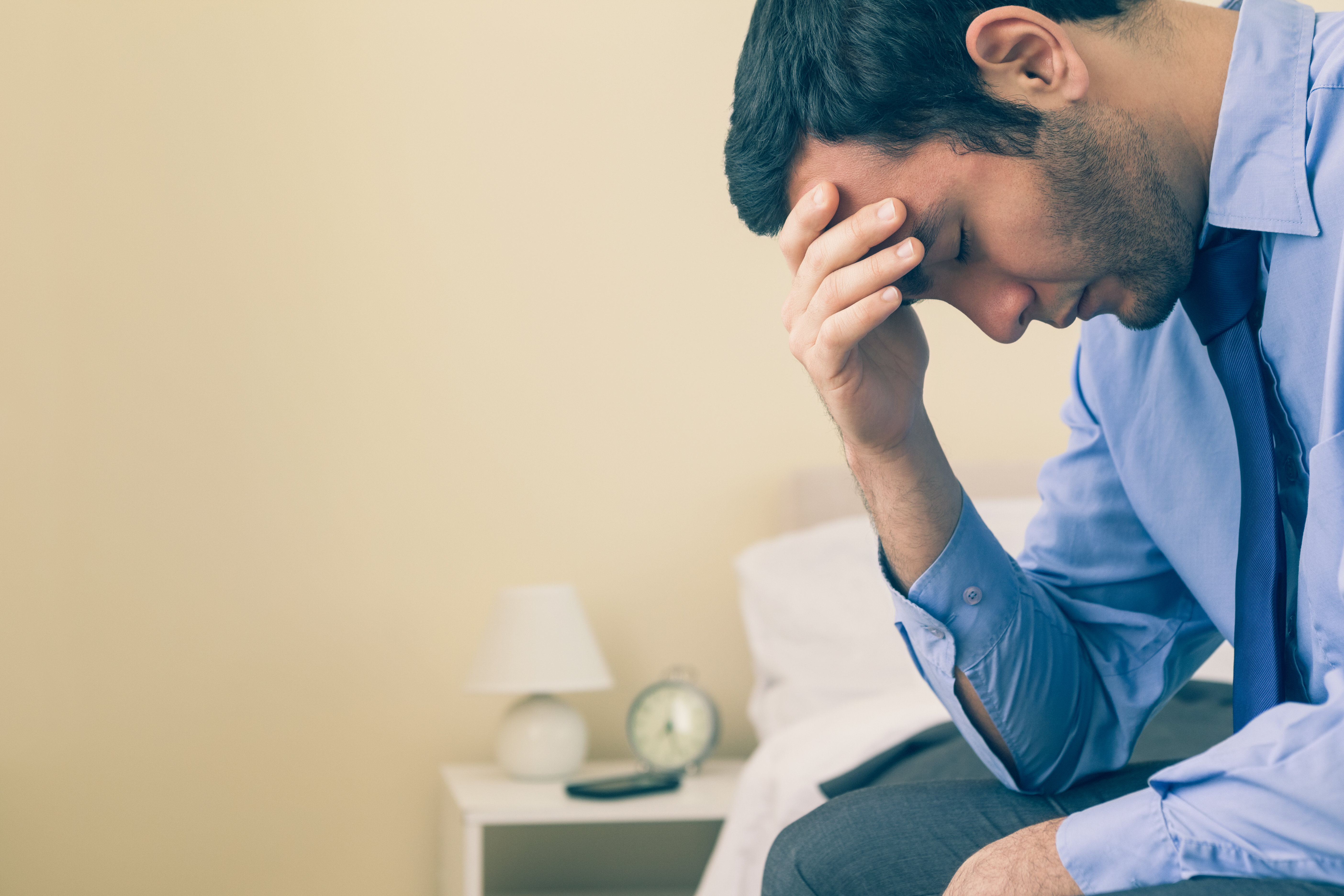 Image of a business man holding his head with his one hand and looking depressed - represents that If you have low self-worth you cannot see on your work only on the goods you sell