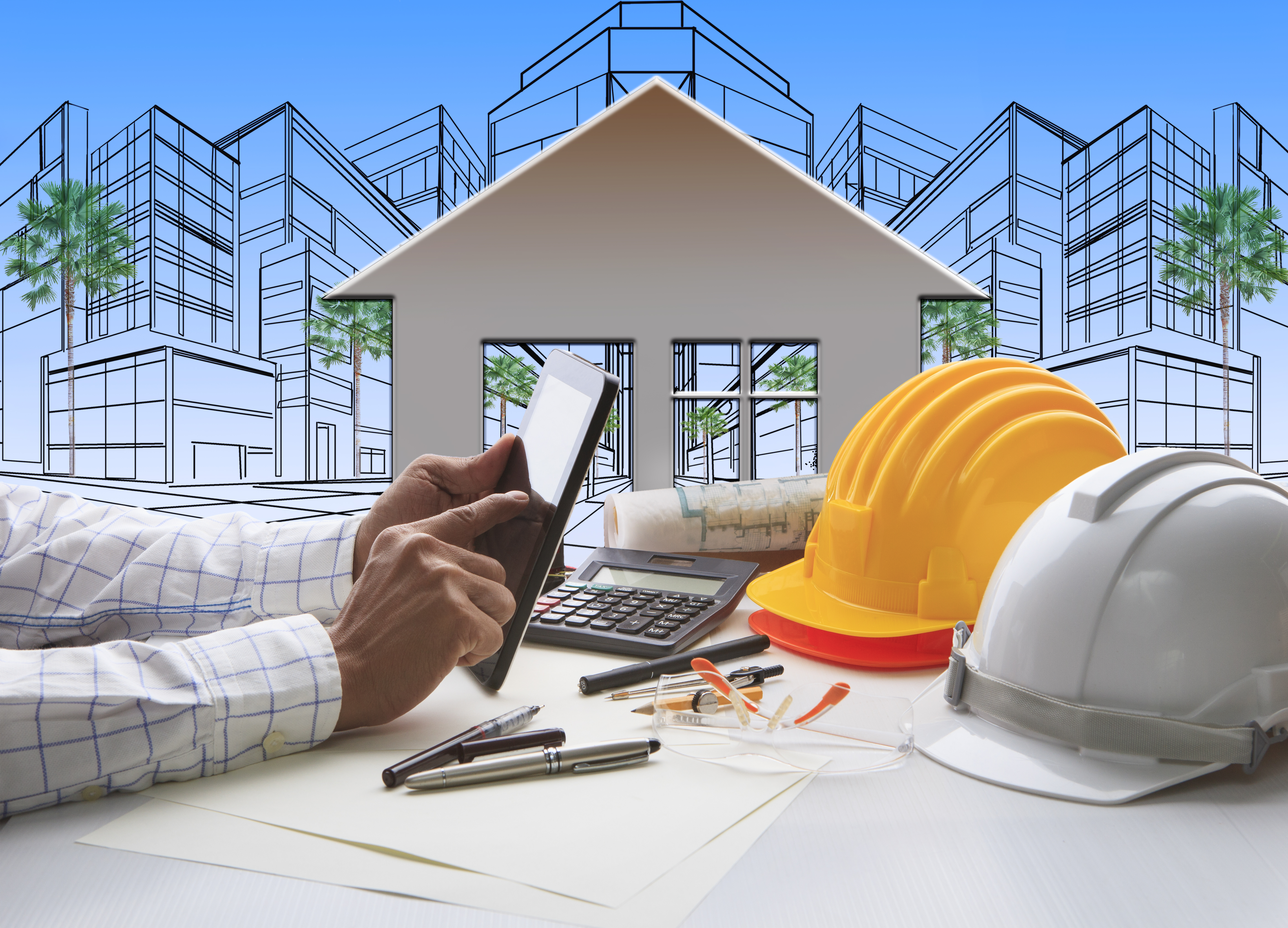 Image of a property investor using a tablet and over a table with builder helmets and blue prints - represents that Another great Property Development Tip is to be sure to find quality builders