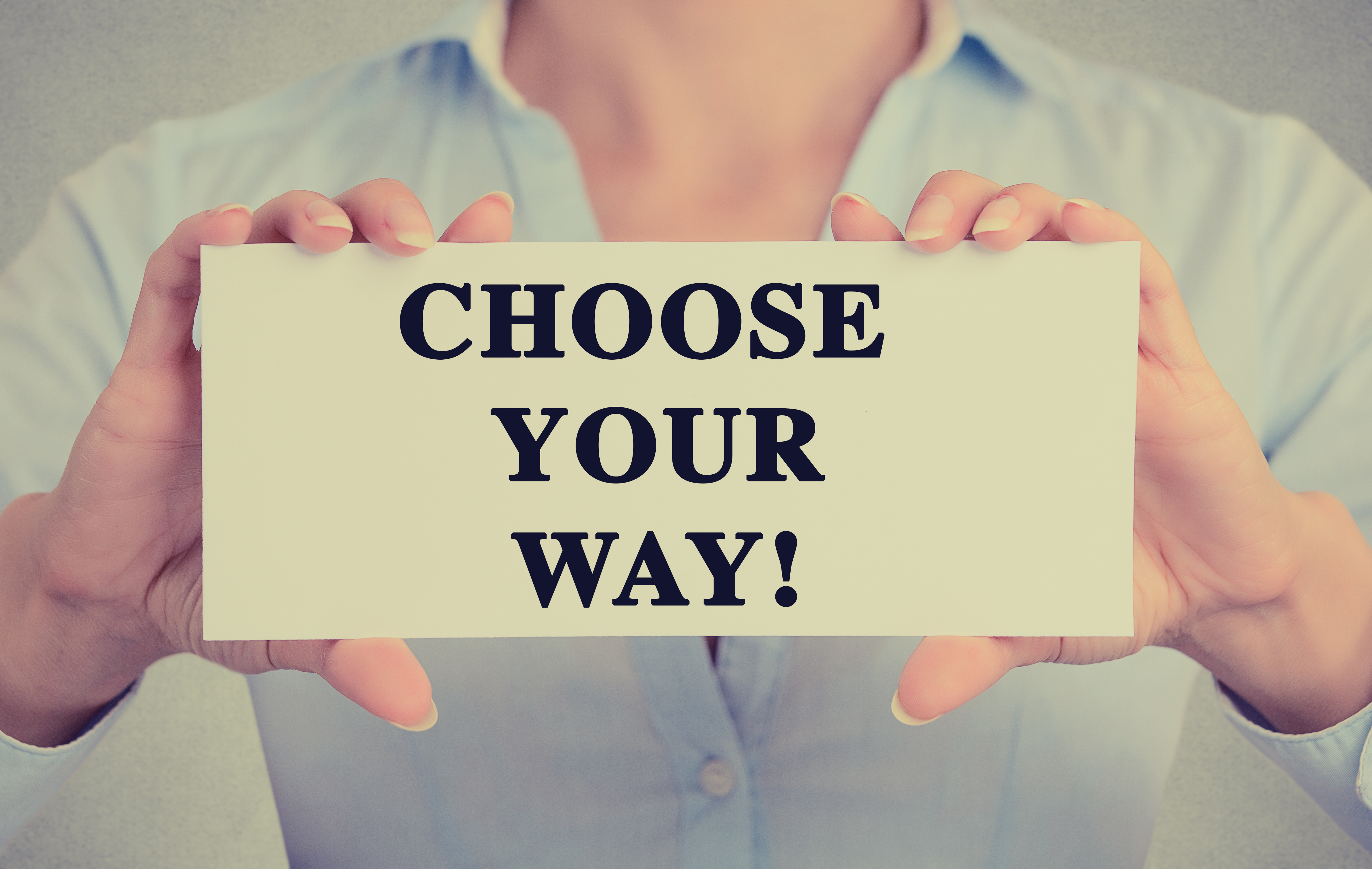 Image of a woman hold a sign saying choose you own way - represents that Choose you own path is on of the best Property Development Tips to remember