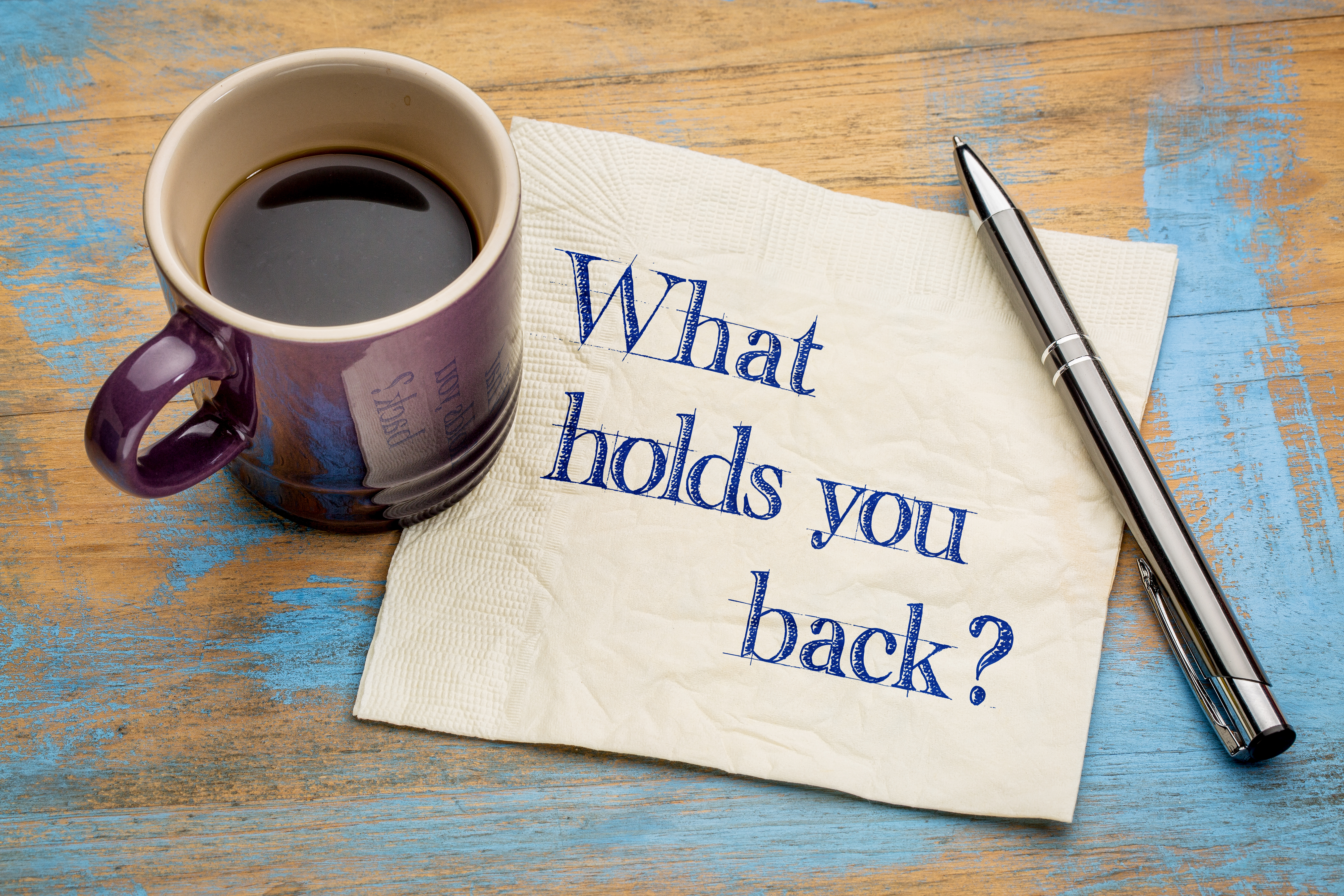 Image of a cup of coffee over a napkin with sentence: what holds you back - represents that you need to Figure out what holds you back and you will be able to Get what you want in life 