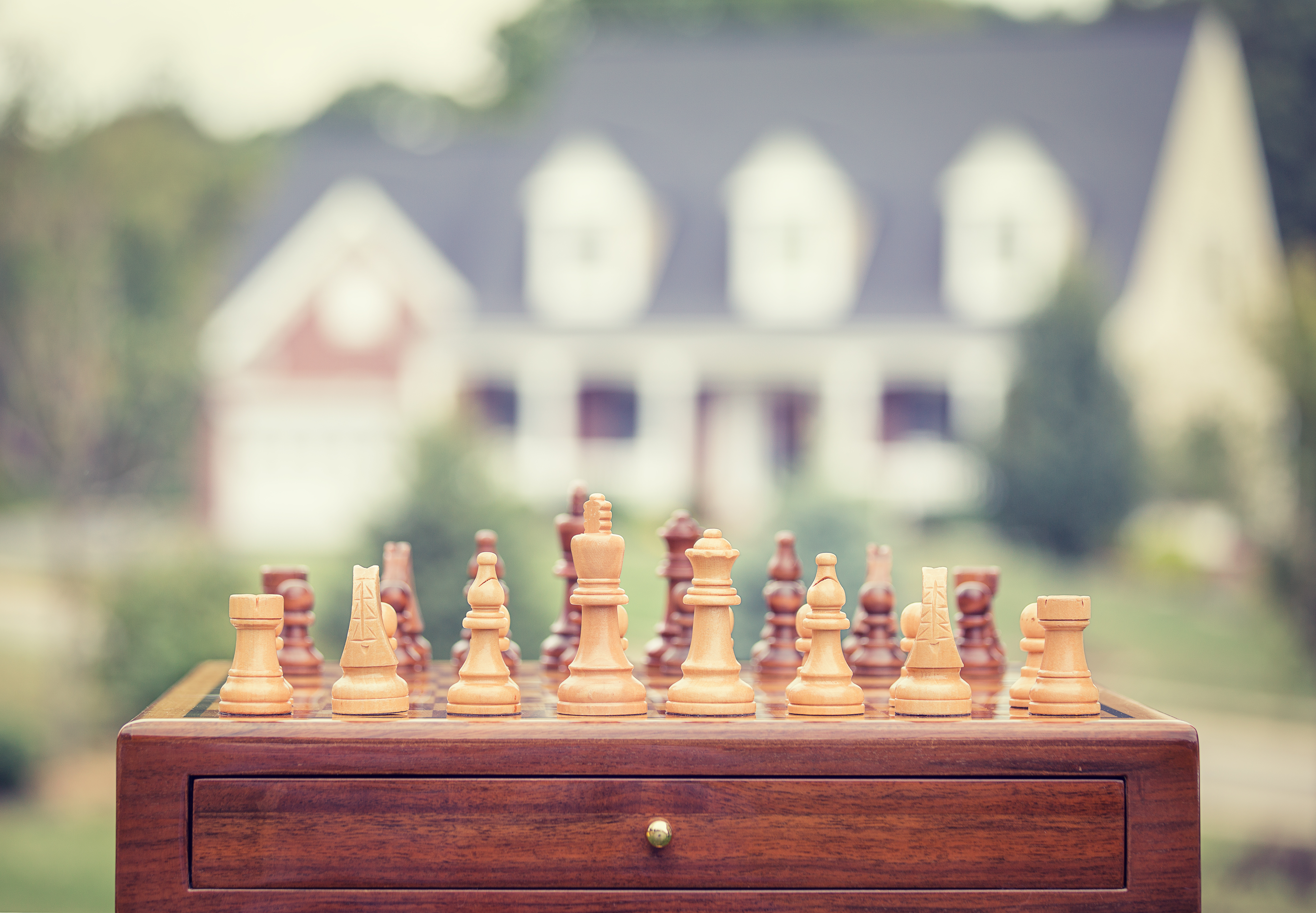 image of a chess boars set in front of a house - represents that you must Choose the Right Property Investing Strategy For You